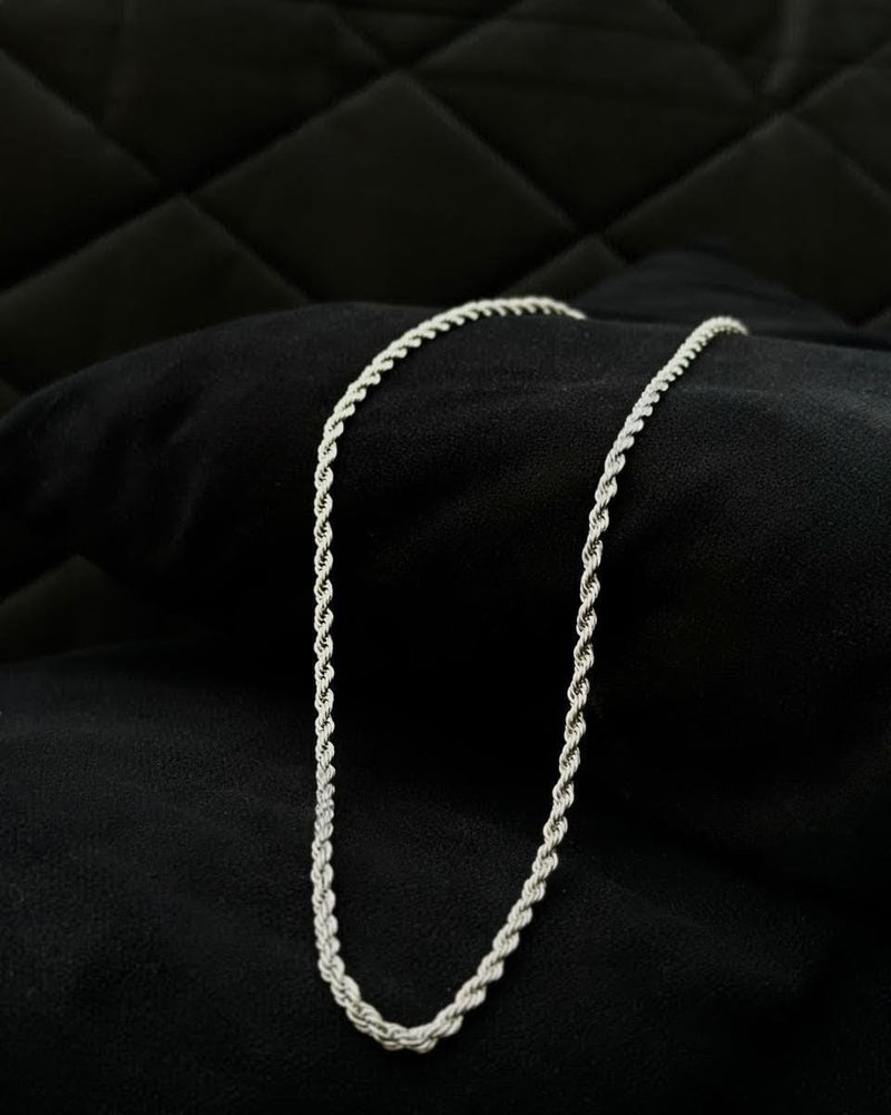 Silver chain necklace on a black textured surface